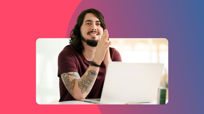 Mann mit langen Haaren und T-Shirt sitzt vor einem Laptop und schaut freundlich