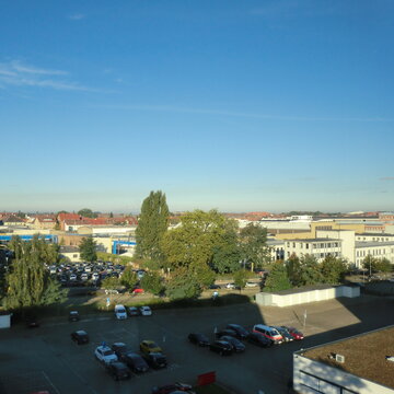 Ausblick vom Standort Braunschweig auf einen Parkplatz, mehreren Bäumen und Wohnhäuser