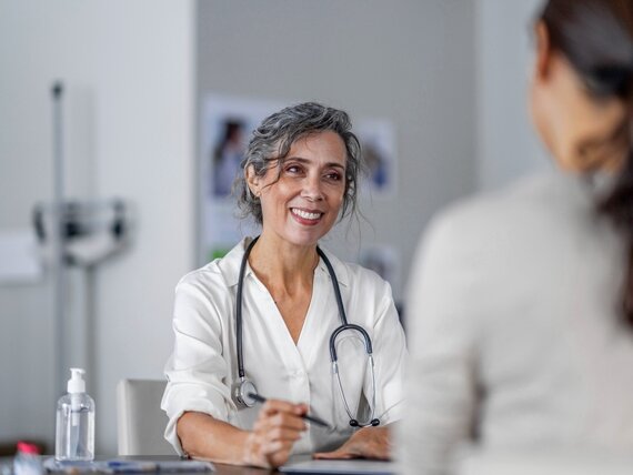 Eine Ärztin unterhält sich mit ihrer Patientin und macht sich Notizen