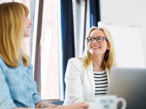 Zwei Frauen reden lachend im Büro
