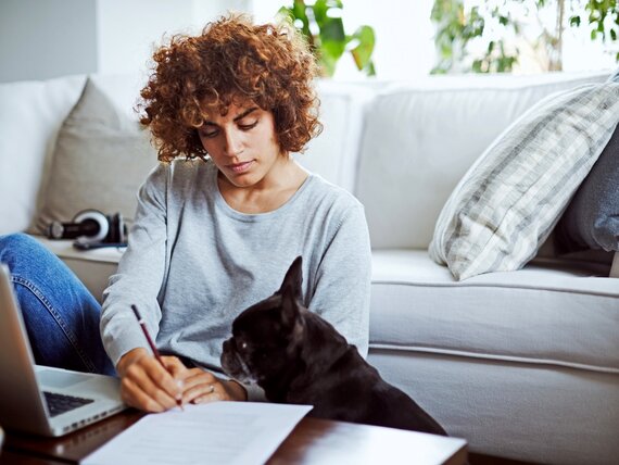 Eine Frau mit Hund arbeitet an ihrem Laptop.