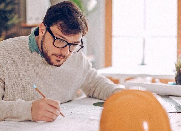 Ein Bauingenieur arbeitet an seinen Planzeichnungen.