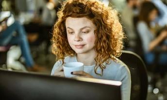 Eine junge Frau sitzt vor einem Computerbildschirm.