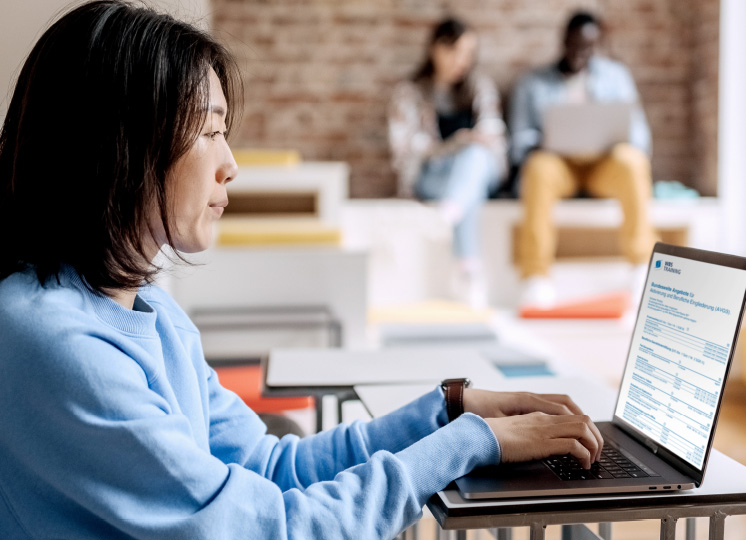 Eine Frau sitzt vor dem Laptop und recherchiert nach einer AVGS Weiterbildung.